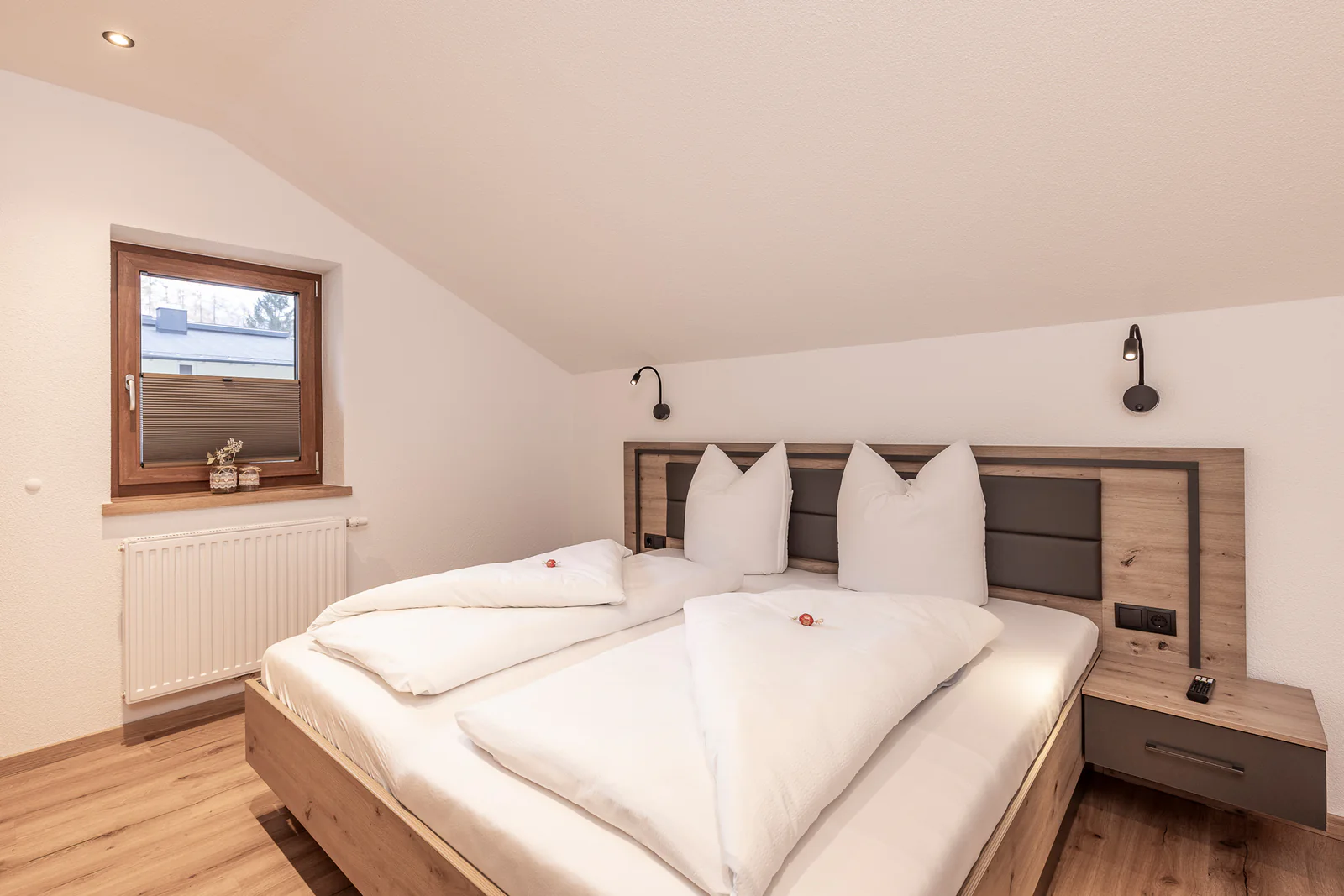 Schlafzimmer unter der Dachschräge: Doppelbett mit Kopfteil und Fenster