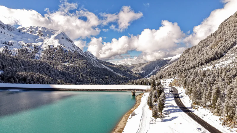 Türkisblauer Speichersee zwischen verschneiten Bergen